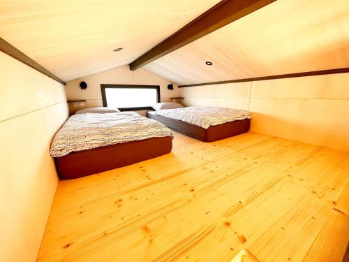 绍莱tiny house的小型客房铺有木地板,配有两张床。