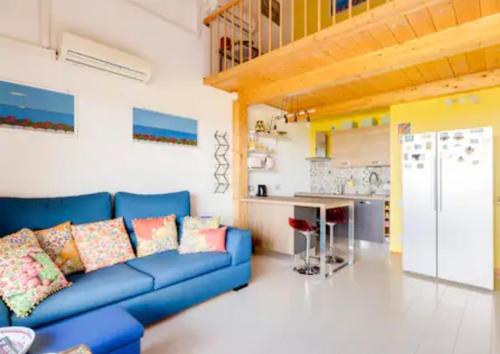 圣玛格利特迪普拉Villa Bellavista IS MOLAS PULA, CAGLIARI的一间带蓝色沙发的客厅和一间厨房