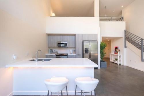 洛杉矶1500 Sq foot, 3 bed room loft in DTLA (Pool & Hot tub!)的厨房配有柜台和2张白色凳子