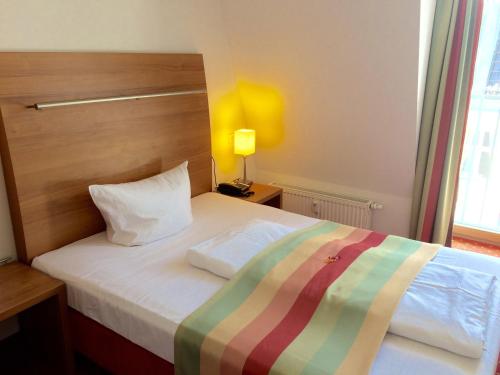 柏林安博特酒店的一间卧室配有一张床,床上有条纹毯子