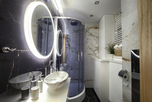 瓦多维采Apart Dwudziestolecie的浴室配有盥洗盆和带镜子的淋浴