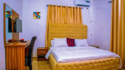 阿沙巴KUNN Apartments的一间卧室配有一张带黄色床头板的床和一张书桌