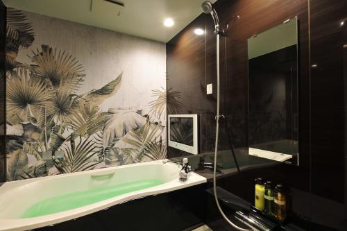 丰中HOTEL the QUEEN的一间带绿色浴缸的浴室,配有热带壁纸