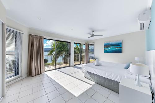 埃尔利海滩Whitsunday Beachfront Apartment on Broadwater的白色卧室设有大床和大窗户