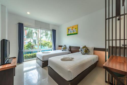 查龙The One Cozy Vacation Residence SHA Hotel的一间卧室设有两张床、一台电视和一扇窗户。