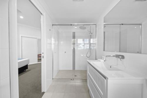 洛坎普顿CocoBrew Boutique Apartments的带淋浴和盥洗盆的白色浴室