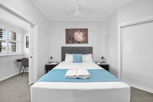 洛坎普顿CocoBrew Boutique Apartments的白色卧室配有一张大床和两条毛巾