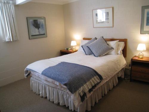 HowrahBreakfast Provisions Provided With Harbour View的一间卧室配有一张大床、两张桌子和两盏灯。