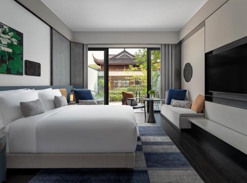 苏州苏州金普顿竹辉酒店的卧室配有白色的床和电视