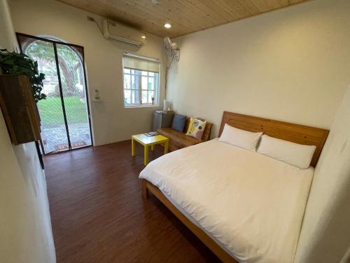 南湾愛玩生活墾丁聚所的卧室配有白色的床和窗户。