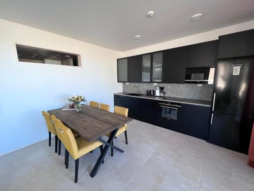 卡拉约基Villa Resort Apartments by Hiekka Booking的厨房配有木桌、椅子和冰箱。