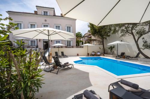 木洛希尼Villa Cassia的房屋旁的游泳池配有椅子和遮阳伞