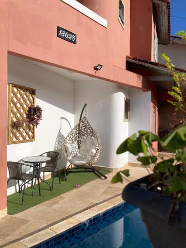 大普拉亚Casa lazer completo 200m da praia的一座带椅子和桌子的庭院位于一座建筑旁边