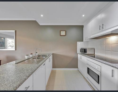 穆尔瓦拉Golf Views Apartment的白色的厨房设有水槽和台面