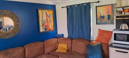 RocbaronChez Nat的客厅设有棕色沙发和蓝色的墙壁。