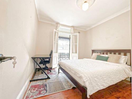 悉尼Pyrnmont Terrace & Townhouse的一间卧室配有一张床、一张桌子和一个窗户。