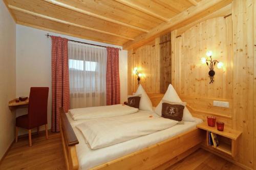 茨维泽尔Wenzlhof的木制客房内的一间卧室,配有一张床