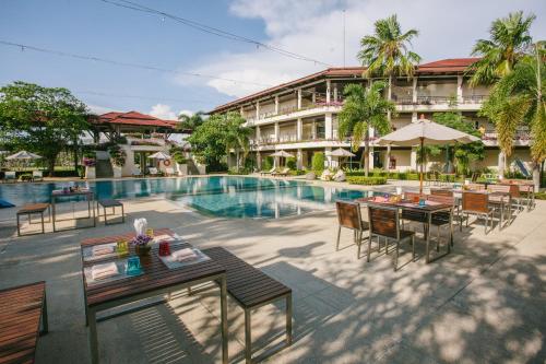 尖竹汶Maneechan Resort - SHA Extra Plus的一座带游泳池和桌椅的度假村的形象