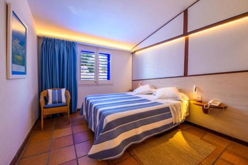 卡达克斯Hotel Blaumar Cadaqués的一间卧室配有一张带蓝白条纹毯子的床