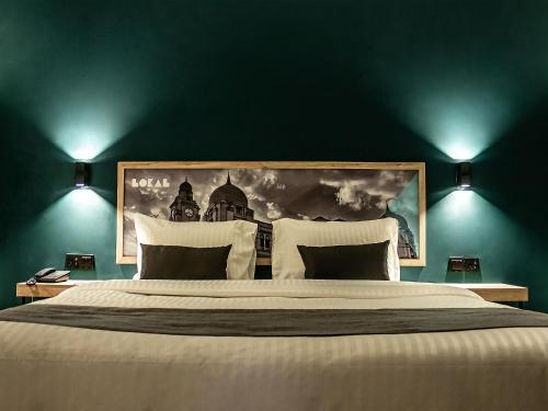 卡拉奇LOKAL Rooms x Shahrah-e-Faisal (Nursery)的卧室配有一张大床,墙上挂有绘画作品