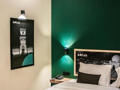卡拉奇LOKAL Rooms x Shahrah-e-Faisal (Nursery)的一间卧室设有绿色的墙壁、一张床和一盏灯