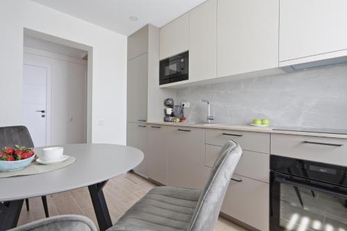 乌田纳Aušros apartamentai的厨房配有白色橱柜和桌椅