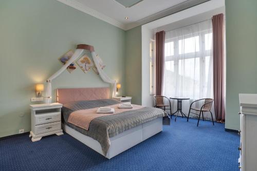 玛丽亚温泉Aphrodite Hotel Marianske Lazne的一间卧室配有一张大床和一张桌子