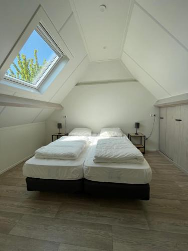 东卡佩勒Hèt Koetshuis的白色的阁楼卧室配有一张带窗户的床