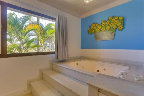 朱奎Chez Louise et Louis Pé na Areia的带浴缸的浴室和带盆栽的窗户