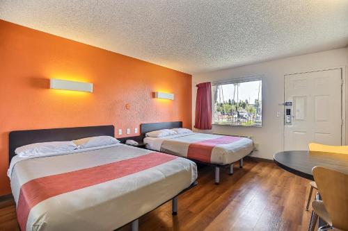 奥克兰艾姆巴克德拉欧克兰6号汽车旅馆的酒店客房设有两张床、一张桌子和一个窗户。