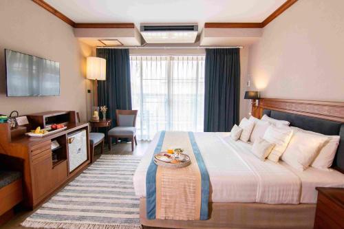 乌汶Tohsang Heritage Ubon Ratchathani Hotel的酒店客房设有一张大床和一台电视。