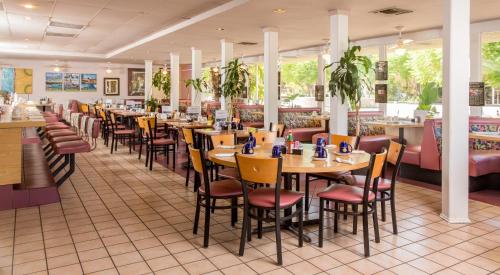 棕榈泉棕榈泉戴斯酒店的用餐室配有桌椅