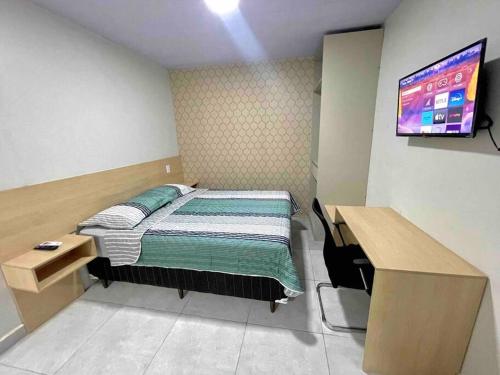 马卡帕Apartamento Studio Centro的一间卧室配有一张床、一张书桌和一台电视