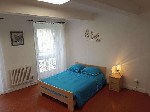 PuimoissonLa Maison de la Cloche的一间卧室配有一张带蓝色床单的床和一扇窗户。