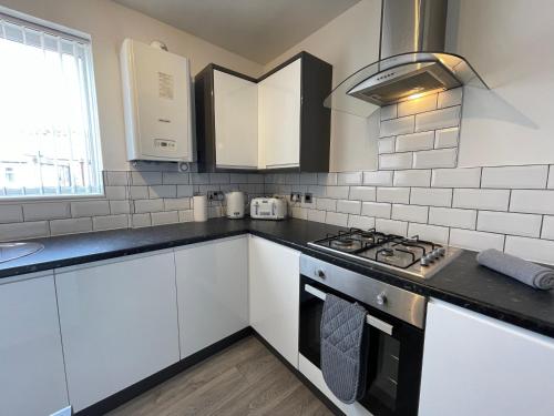 泰恩茅斯Jacksons Modern Retreat Close to Tynemouth的厨房配有白色橱柜和炉灶烤箱。
