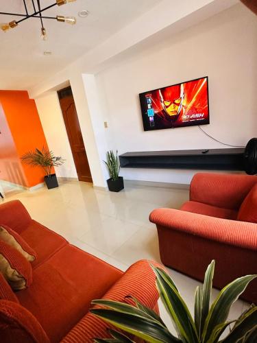 阿亚库乔Castellares la Puebla Hostelería Departamento的客厅配有橙色家具和平面电视。