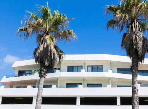 悉尼Bondi Beach Waves Beachfront Apartment的一座白色的建筑,前面有棕榈树