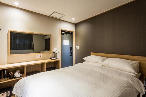 首尔About Stay Seoul的卧室配有一张白色大床和电视。