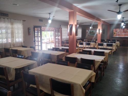 若阿诺波利斯Pousada Solar das Palmeiras的一间设有白色桌椅的用餐室