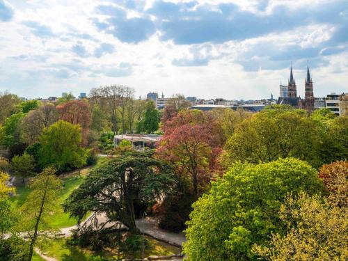 安特卫普Mercure Antwerp City Centre的享有树木和建筑公园的景色