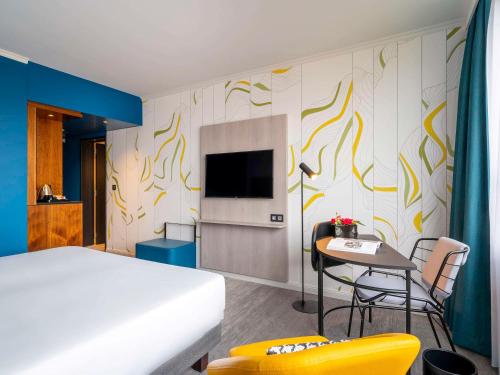 安特卫普Mercure Antwerp City Centre的一间卧室配有一张床、一张桌子和一台电视。