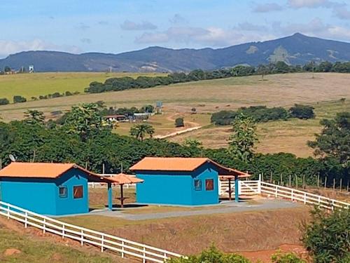 圣托梅-达斯莱特拉斯Chales Horizonte das Pedras的两栋蓝色小屋,位于带围栏的场地内