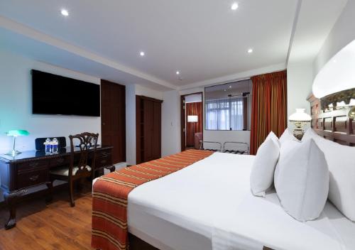 库斯科泰拉安迪纳殖民地庄园酒店的卧室配有一张白色大床和一张书桌