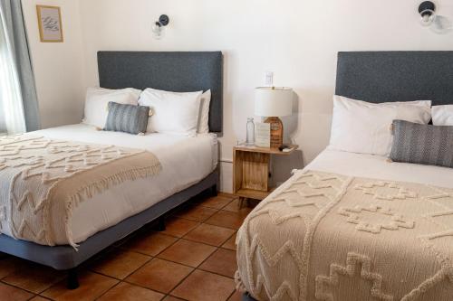 危地马拉安地瓜Mestizo Antigua的一间铺有瓷砖地板的卧室,配有两张床和一盏灯。