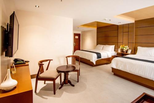长滩岛ECL Resort Hotel Boracay的酒店客房,设有两张床和一张桌子及椅子