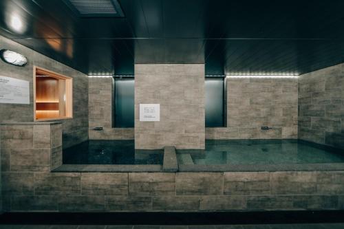 平冢市3s HOTEL HIRATSUKA的一间设有浴缸的客房,墙上挂着一个时钟