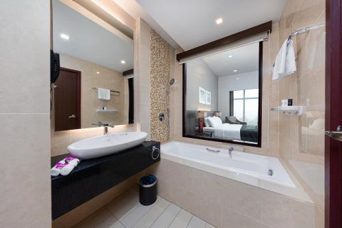 古晋Raia Hotel & Convention Centre Kuching的一间带水槽和浴缸的浴室以及一张床