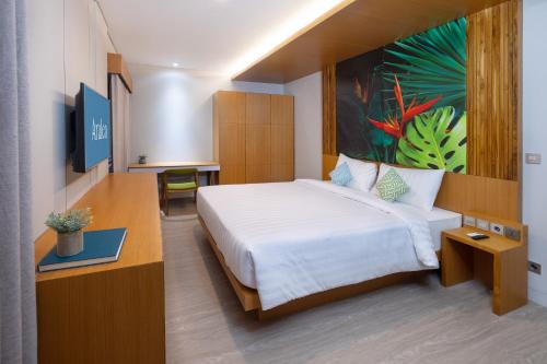 登巴萨Aralea Coliving的酒店客房设有一张床,墙上挂有绘画作品