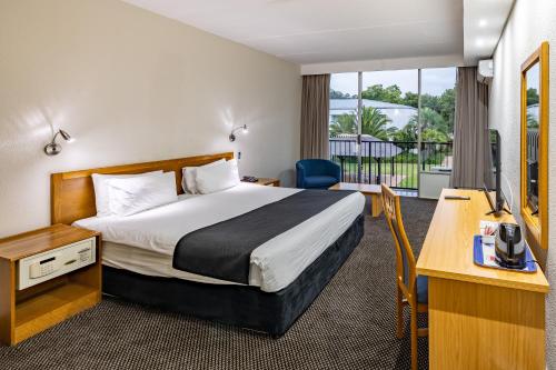 纽卡斯尔African Sky Newcastle Inn的配有一张床和一张书桌的酒店客房