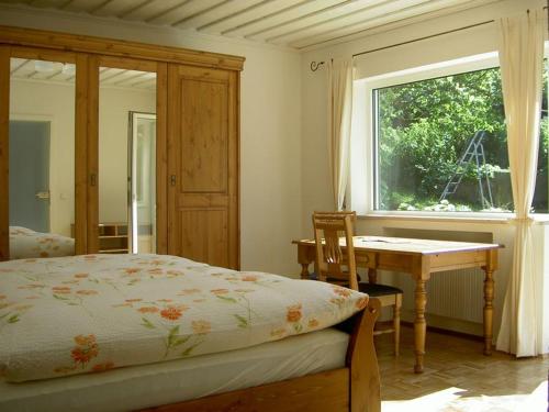 基姆湖畔普林Gästehaus Ehrlich的一间卧室配有一张床、一张桌子和一个窗户。